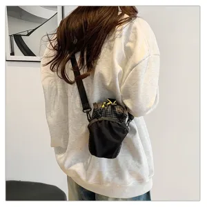 Back view of a female model wearing a black functional outdoor crossbody phone bag