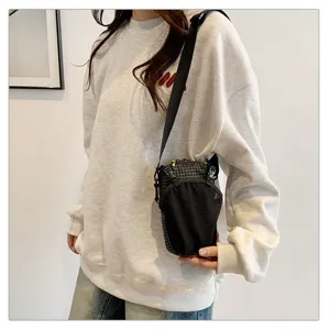 Black ripstop grid outdoor crossbody phone pouch shown on a model for hiking use.