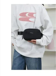 Detail view of a black minimalist waist bag worn by a model in casual style