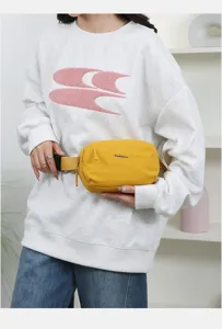 Detailed view of a yellow minimalist portable waist bag styled with a white casual sweatshirt