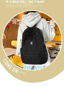 Zwarte gewatteerde rugzak met ruitpatroon gedragen door model in een café