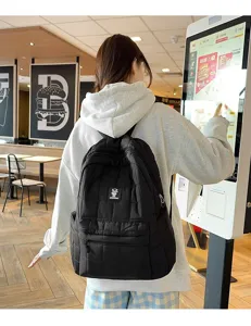 Zwarte gewatteerde rugzak met logo getoond in een casual lifestyle-omgeving