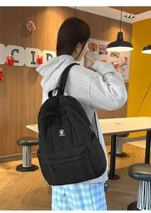 Achteraanzicht van een zwarte gewatteerde rugzak gedragen door een model in cafe