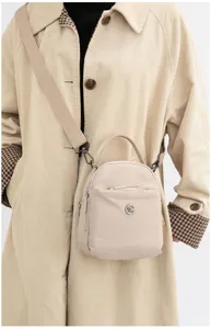 Vista detallada de la mini mochila cruzada de nailon en color beige con varios bolsillos.