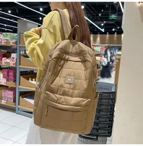 Gedetailleerd overzicht van een bruine gewatteerde minimalistische rugzak voor dames op model