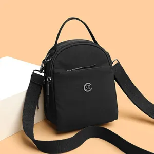 Mini bolso cruzado negro de tela oxford con asa superior y bolsillos múltiples.