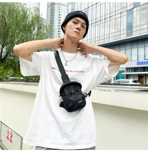 Close-up detail shot of a black camo outdoor chest bag worn by a model in urban style