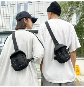 Rear view of trendy black crossbody sling bags worn by models in an urban setting