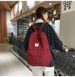 Achteraanzicht van een student met een bordeauxrode gewatteerde rugzak in een winkel