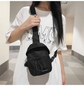 Close-up view of a stylish black nylon chest bag worn by a person in a white t-shirt