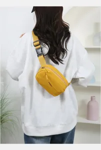 Detail view of a vibrant yellow crossbody bag worn by a model in a casual indoor setting.