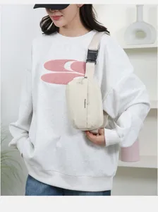 Close-up of a model wearing a minimalist cream chest bag in a bright indoor setting