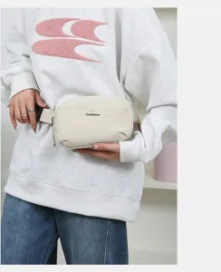 Close-up of a cream minimalist fanny pack worn by a model in a casual setting