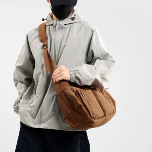 Detailed view of large capacity waterproof brown messenger bag with front zipper pockets.