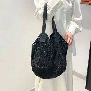 Zwarte gebreide shopper detailweergave met fijne gehaakte textuur en lederen handvatten.