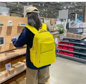 Detailed lifestyle view of a bright yellow canvas student backpack in a retail store setting.