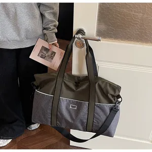 Détail du grand sac de voyage avec motif à carreaux, tissu vert et sangles de transport solides.