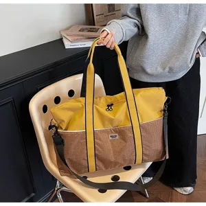 Vue détaillée du grand sac de sport et de voyage quadrillé jaune et marron avec poignées.