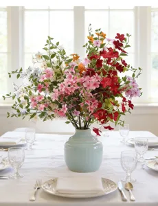 Elegant artificial flower bouquet in a blue vase on a set dining table