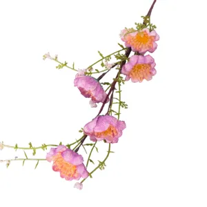Primer plano de flores artificiales rosas con estambres amarillos y hojas verdes.