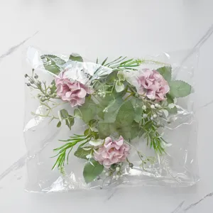 Close-up detail of artificial pink hydrangea flowers with green leaves and berries in package.