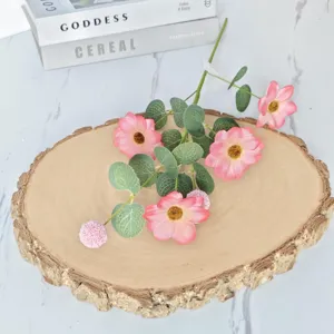 Gros plan d'eucalyptus artificiel et de cosmos roses sur socle en bois