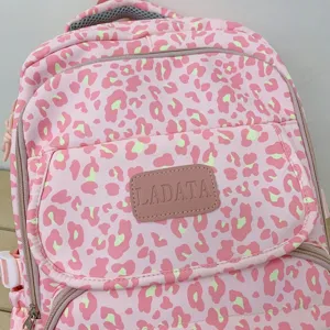 Close-up detail of a pink leopard print backpack featuring a stylish LADATA logo patch
