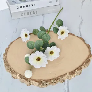 Détail d'une branche d'eucalyptus artificiel avec marguerites sur tranche de bois