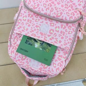 Close-up of pink leopard print backpack showing front pocket storage with a magazine