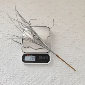 Gros plan d'une branche de Noël pailletée argentée de 43 cm pesant 14 grammes sur balance