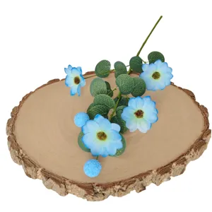 Marguerites bleues artificielles avec feuilles d'eucalyptus sur une base de tranche de bois