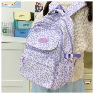 Side view of a purple leopard print large capacity backpack shown being worn by a student