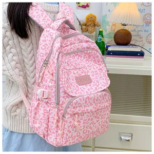 Detailed view of pink leopard print backpack worn by a student in a cozy room.