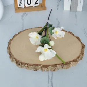 Detailed view of three-headed white artificial poppy flowers on a rustic wood slice