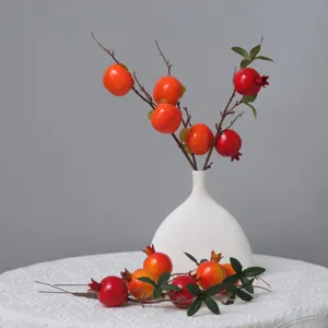 Dettaglio ramo artificiale di melograno cachi, accessorio decorativo floreale molto realistico.