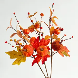 Detailed view of artificial autumn pumpkin and maple leaf branch for home seasonal decor.
