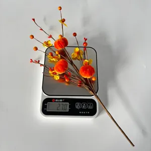 Close-up detail of artificial autumn persimmon branch with berries for home decor display.