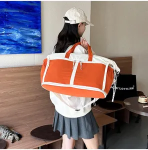Detailed side view of large orange and white travel duffel bag on model's shoulder