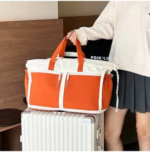 Detail view of large orange travel bag on white suitcase showing handle and size