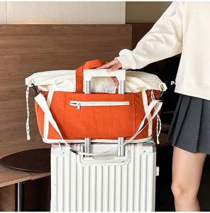 Detail showing orange travel bag sleeve attached to white suitcase handle for travel.