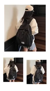 Black large-capacity school backpack for female students shown from back view on stairs.