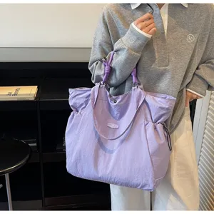 Large capacity purple waterproof travel tote bag carried by a model in casual setting.