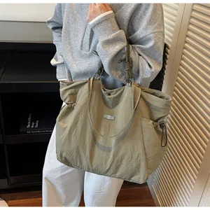 Side view of an olive green large capacity waterproof travel tote bag carried by a model