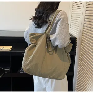 Lifestyle view of a large olive green waterproof commuter tote on a model's shoulder.