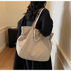 Large beige waterproof tote bag shown being carried over the shoulder in a lifestyle setting