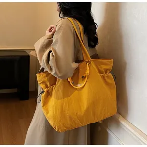 Detailed side view of a large yellow waterproof tote bag being carried by a fashion model