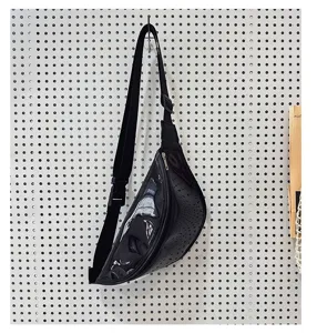 Close-up detail of the stylish black glossy chest bag showing texture, zipper, and strap.