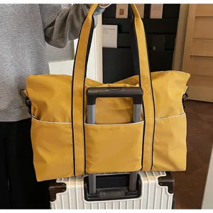 Grand sac de voyage jaune avec sangle pour valise, idéal pour le sport et fitness.