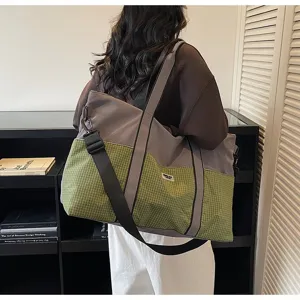 Vue détaillée d'un grand sac de sport à motif à carreaux vert et design gris, porté sur l'épaule.