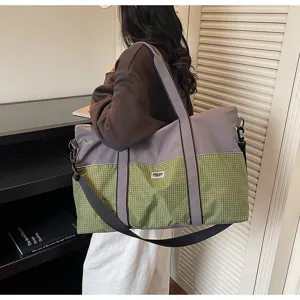 Vue de détail d'un sac de sport de voyage grand format avec motif à carreaux verts et bandoulière.